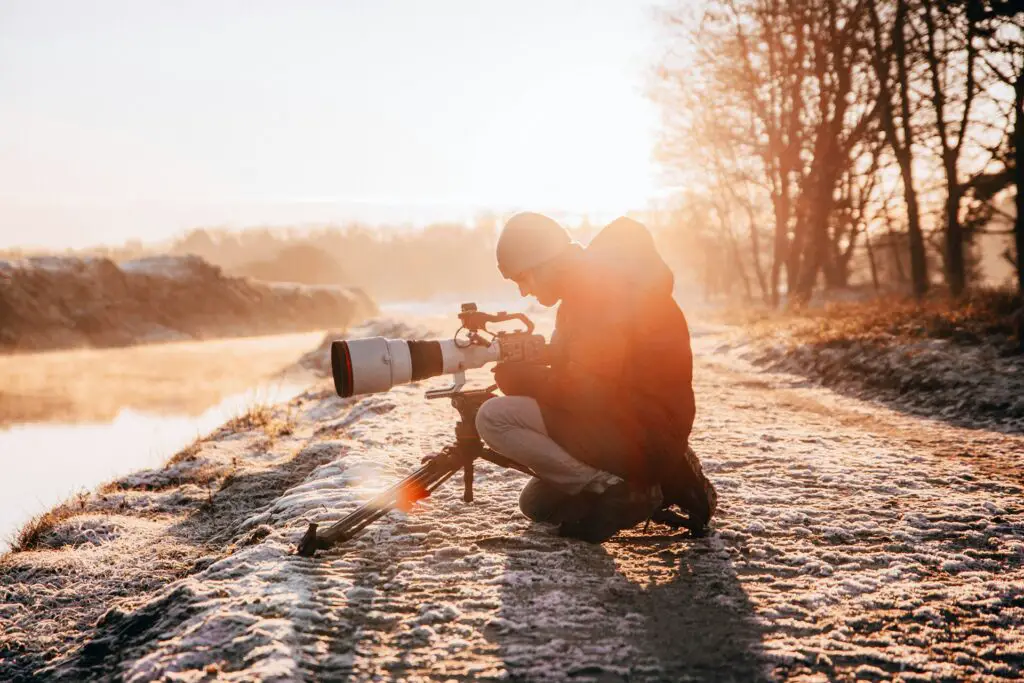 a man sitting on a dirt road with a large camera